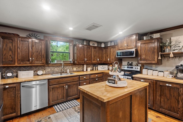kitchen featuring butcher block countertops, a sink, decorative backsplash, stainless steel appliances, and visible vents