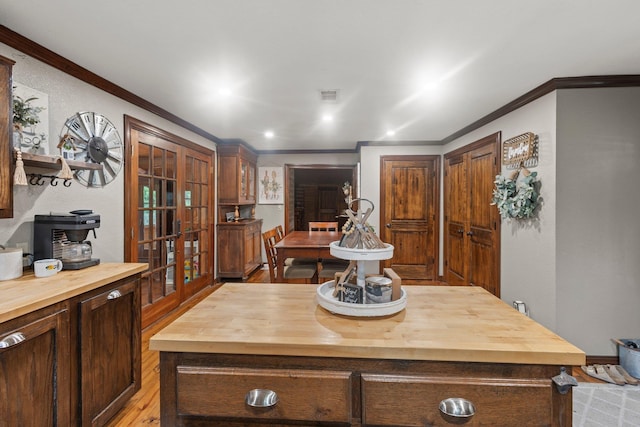 kitchen featuring french doors, light wood-style flooring, visible vents, butcher block countertops, and ornamental molding