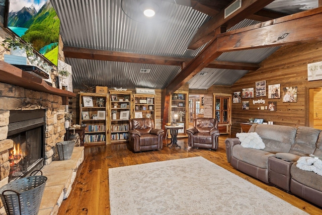 living room with wood walls, visible vents, lofted ceiling with beams, a fireplace, and hardwood / wood-style flooring