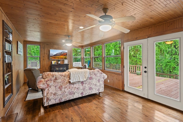 living area featuring wooden walls, hardwood / wood-style floors, wood ceiling, and ceiling fan