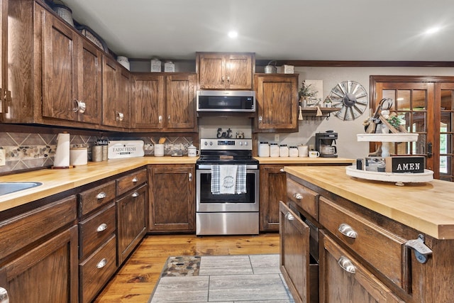kitchen featuring backsplash, light wood-style floors, appliances with stainless steel finishes, and wooden counters