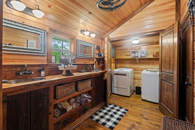 washroom with wood ceiling, wood walls, independent washer and dryer, and a sink
