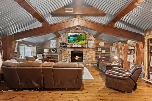 living room featuring hardwood / wood-style flooring, vaulted ceiling with beams, visible vents, and a fireplace