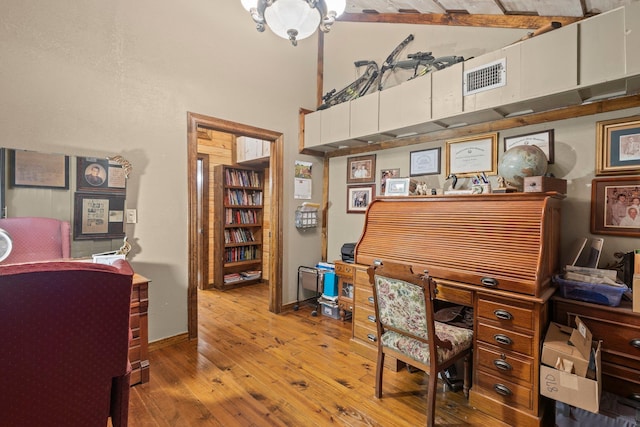office area featuring wood-type flooring, visible vents, baseboards, and a high ceiling