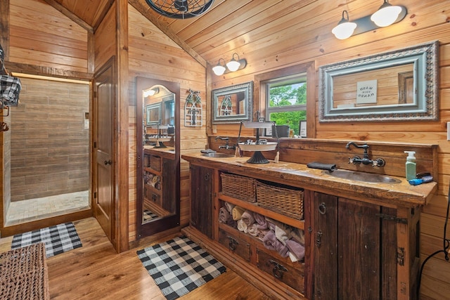 interior space featuring lofted ceiling, wooden walls, wood finished floors, a sink, and wood ceiling