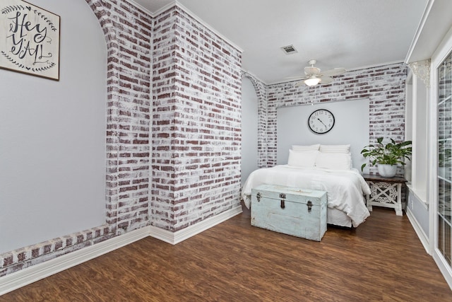 bedroom with crown molding, ceiling fan, dark wood-type flooring, and brick wall