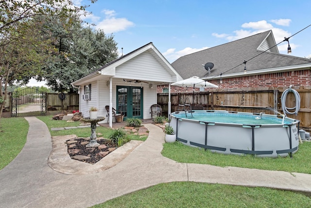 exterior space with a fenced in pool, ceiling fan, and french doors