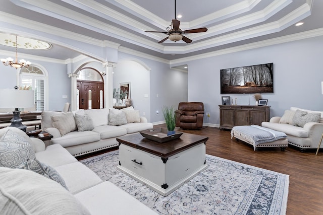 living room with dark hardwood / wood-style flooring, decorative columns, crown molding, and a tray ceiling