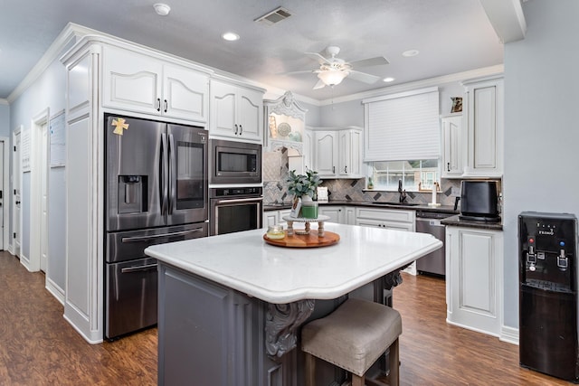 kitchen featuring white cabinetry, a center island, tasteful backsplash, a kitchen breakfast bar, and appliances with stainless steel finishes