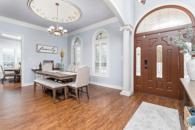 entrance foyer featuring dark hardwood / wood-style floors, an inviting chandelier, crown molding, and decorative columns