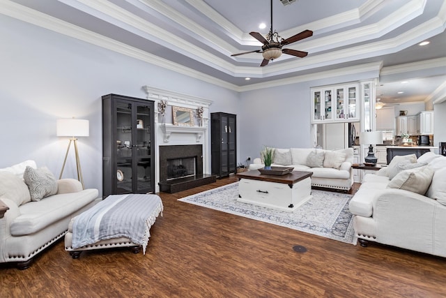 living room featuring a raised ceiling, crown molding, and ceiling fan