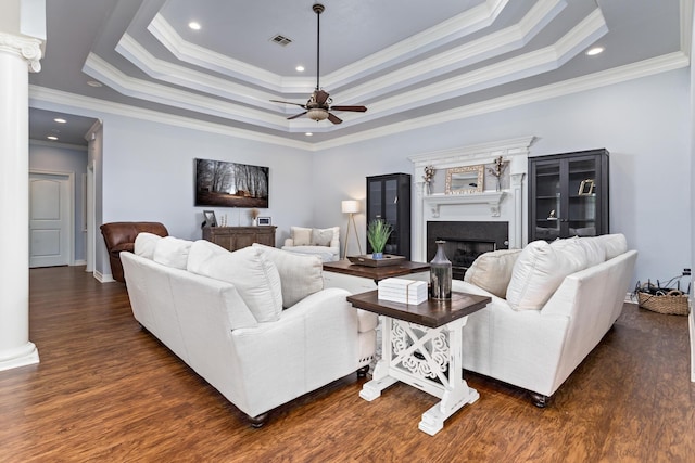 living room with ceiling fan, ornamental molding, dark wood-type flooring, and a tray ceiling