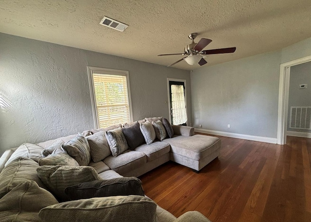 living room featuring ceiling fan, a textured ceiling, visible vents, wood finished floors, and baseboards