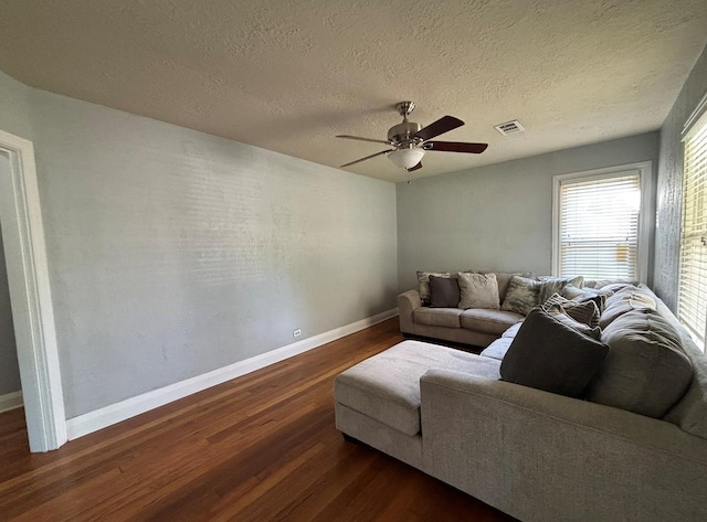 living room with a ceiling fan, a textured ceiling, visible vents, dark wood finished floors, and baseboards