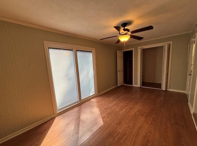 unfurnished bedroom with baseboards, ornamental molding, dark wood-style floors, and a textured ceiling