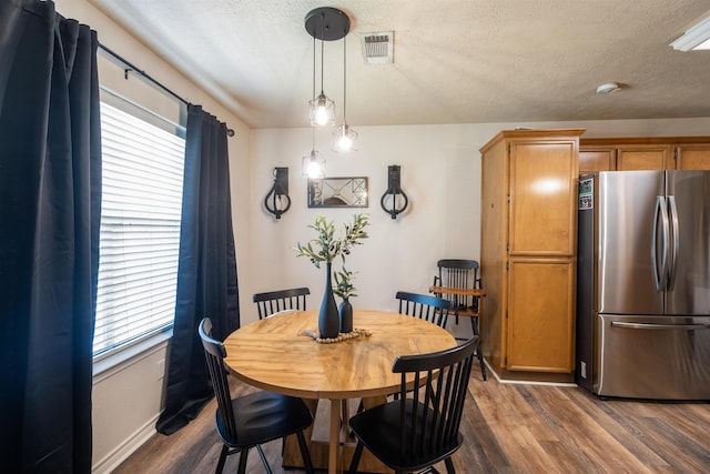 dining area featuring visible vents, a textured ceiling, baseboards, and dark wood finished floors