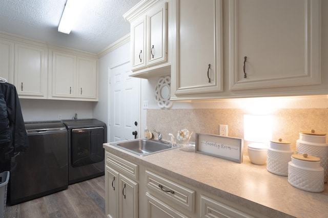 washroom with a sink, a textured ceiling, dark wood-style floors, cabinet space, and washing machine and dryer