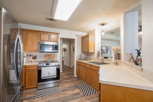 kitchen with light countertops, visible vents, stainless steel appliances, a sink, and wood finished floors