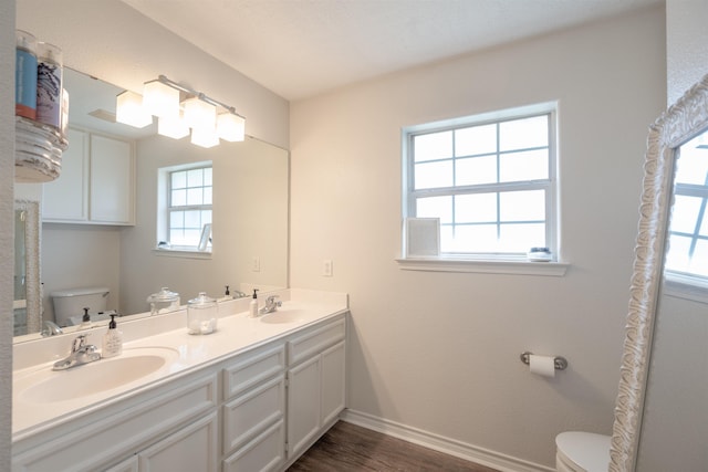 bathroom featuring toilet, wood finished floors, a sink, and baseboards