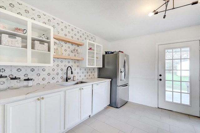 kitchen featuring a sink, backsplash, white cabinets, stainless steel fridge, and open shelves