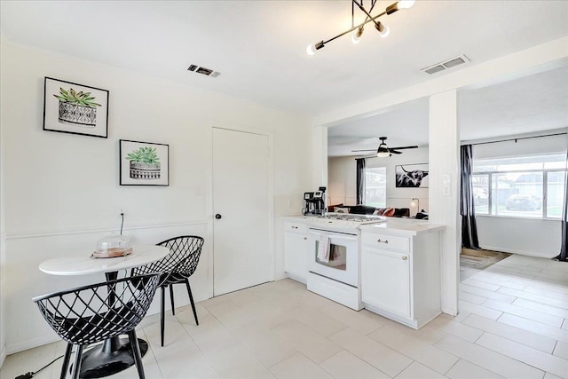 kitchen featuring ceiling fan, visible vents, white gas stove, and light countertops