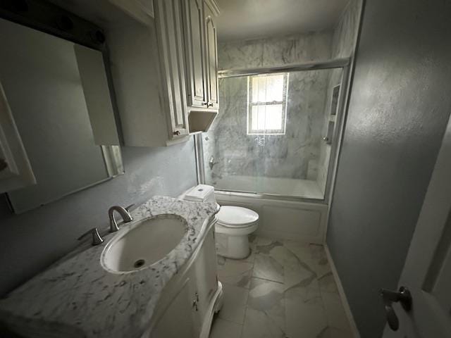full bath with toilet, vanity, enclosed tub / shower combo, marble finish floor, and baseboards