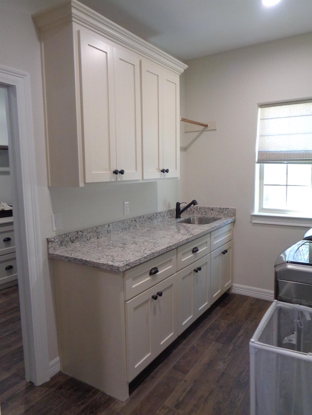 kitchen with a sink, baseboards, dark wood-type flooring, and white cabinets