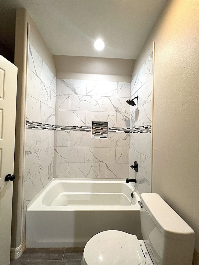 bathroom featuring toilet and tiled shower / bath