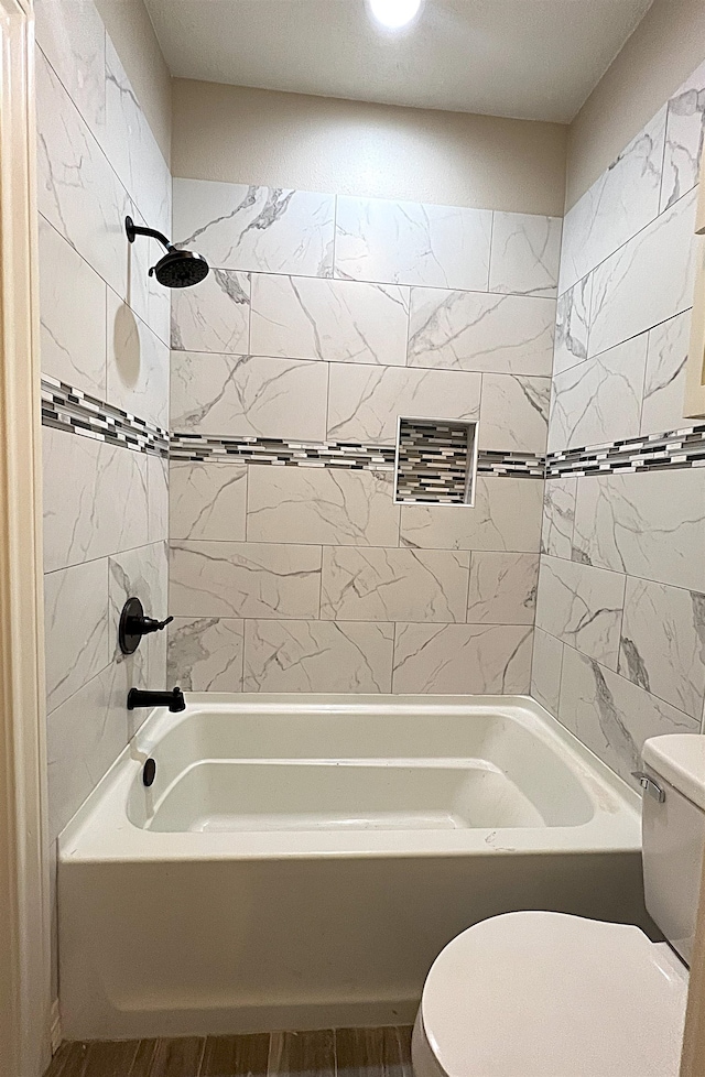 bathroom featuring wood-type flooring, tiled shower / bath combo, and toilet