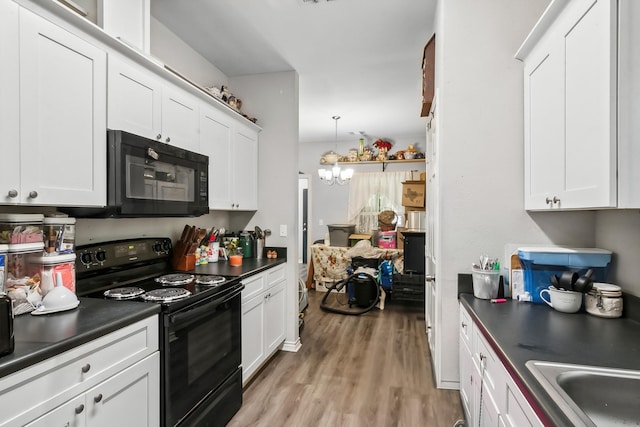 kitchen featuring black appliances, light wood-type flooring, decorative light fixtures, white cabinetry, and a chandelier