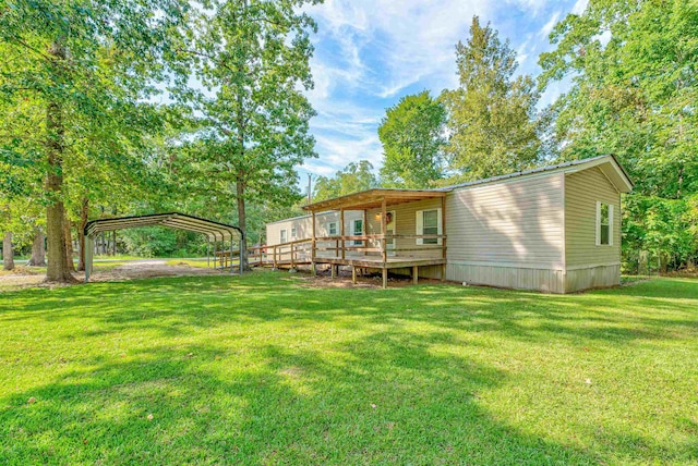 back of property with a wooden deck, a yard, and a carport