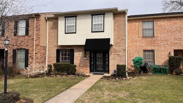 view of front facade with a front yard and brick siding