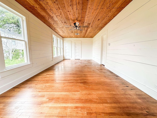 unfurnished sunroom with a healthy amount of sunlight, ceiling fan, and wooden ceiling