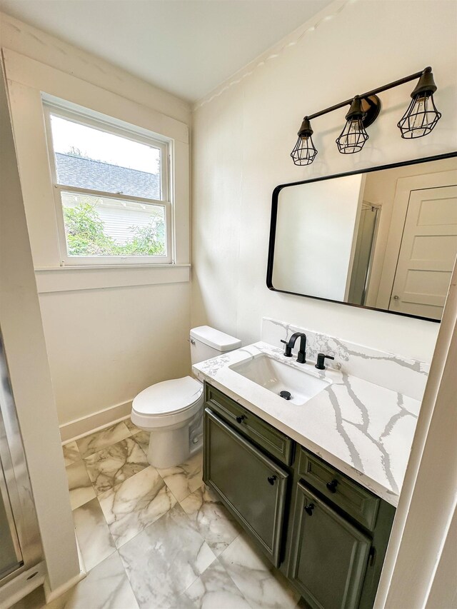 bathroom with a shower with door, vanity, and toilet