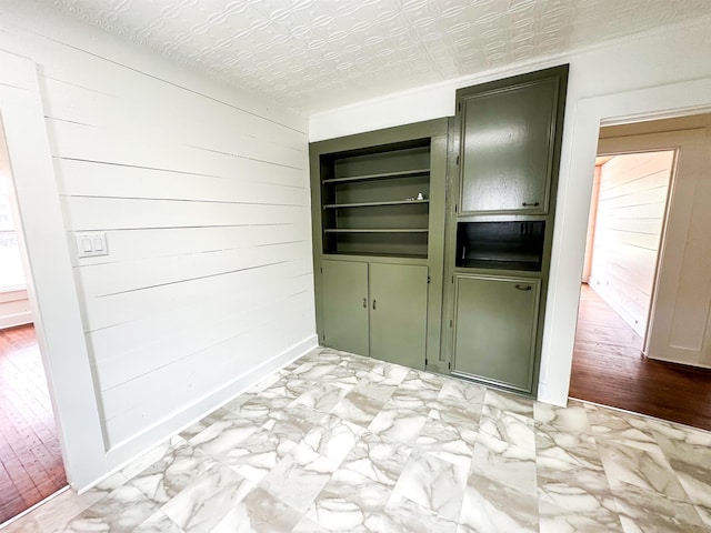 interior space with green cabinets, a textured ceiling, and wooden walls