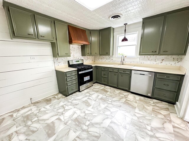 kitchen with pendant lighting, premium range hood, green cabinets, sink, and stainless steel appliances