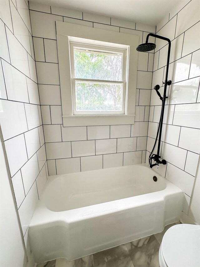 bathroom with tiled shower / bath combo and toilet