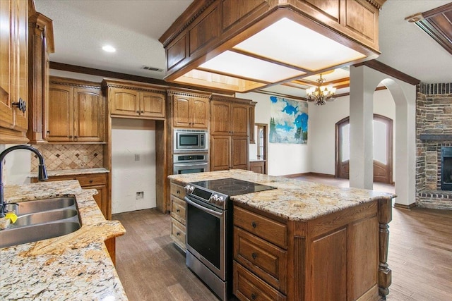 kitchen with decorative backsplash, dark hardwood / wood-style flooring, light stone counters, stainless steel appliances, and sink