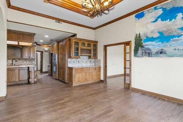 kitchen featuring a notable chandelier, dark hardwood / wood-style flooring, crown molding, and backsplash