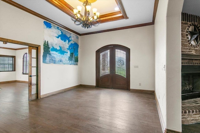 foyer entrance with french doors, an inviting chandelier, a raised ceiling, dark hardwood / wood-style floors, and ornamental molding