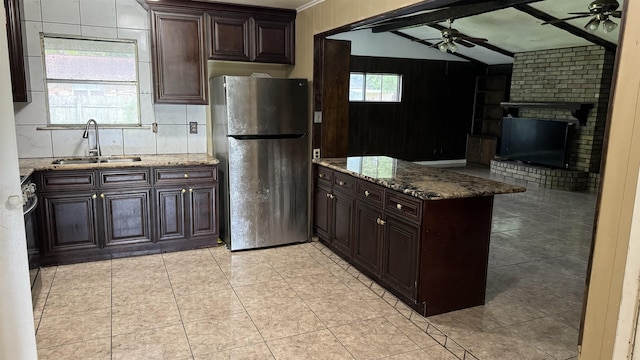 kitchen featuring vaulted ceiling with beams, stainless steel fridge, sink, and stone countertops