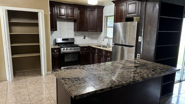 kitchen featuring dark stone countertops, dark brown cabinetry, sink, and appliances with stainless steel finishes