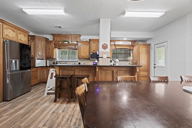 503 Country Wood Cir, Sour Lake, TX 77659 - kitchen featuring appliances with stainless steel finishes, dark countertops, tasteful backsplash, light wood-style flooring, and brown cabinetry