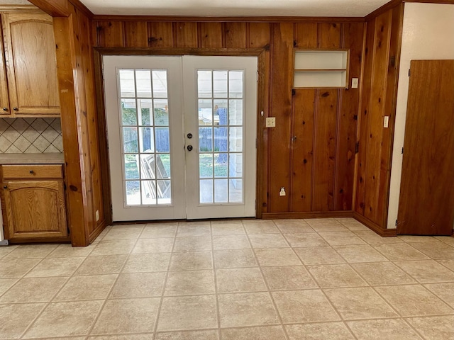 entryway with light tile patterned flooring, wooden walls, and french doors