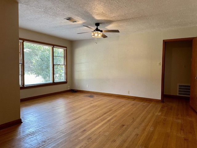 empty room with a textured ceiling, light hardwood / wood-style floors, and ceiling fan