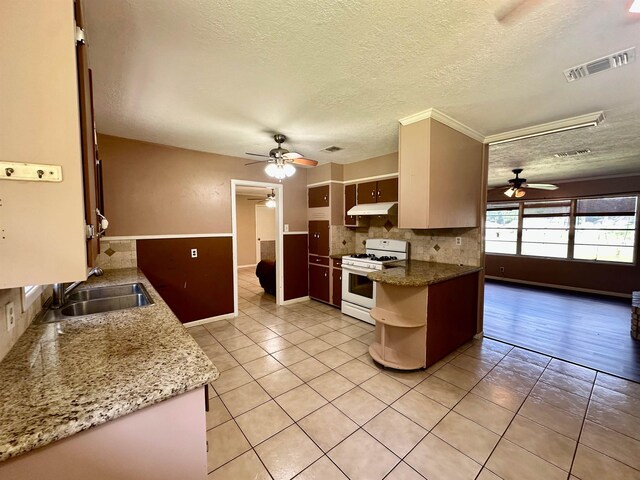 3605 Lawn Oak Dr, Orange, TX 77632 - kitchen with white range with gas stovetop, ceiling fan, a sink, under cabinet range hood, and a textured ceiling