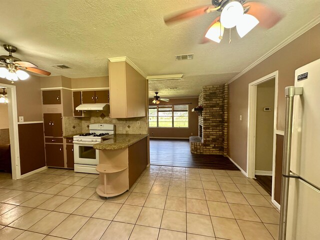 3605 Lawn Oak Dr, Orange, TX 77632 - kitchen with white appliances, light tile patterned floors, ceiling fan, decorative backsplash, and a brick fireplace