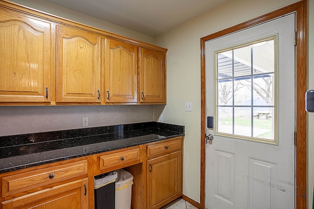 kitchen featuring built in desk and dark stone counters