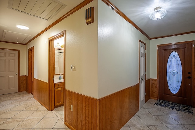 entryway featuring light tile patterned floors, crown molding, and wooden walls