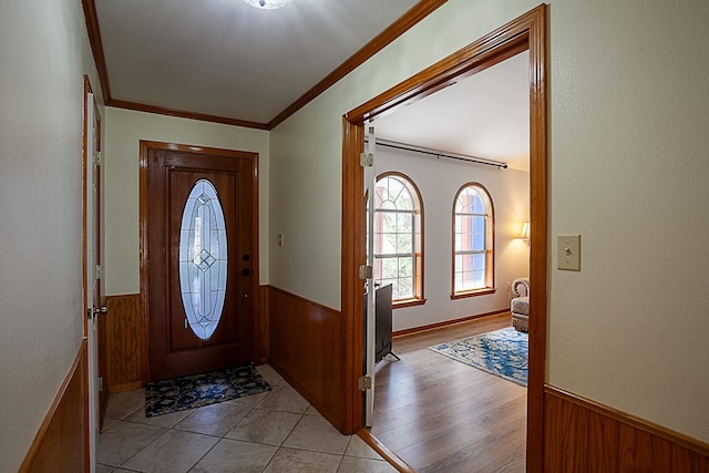 foyer with ornamental molding, light wood-type flooring, and wood walls